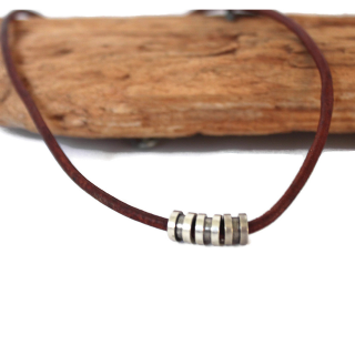 brown-leather-silver-cylinder-necklace-against-wood-white-background