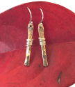 short gold stick earrings on red leaf