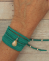 Teal suede wrap bracelet on wrist on wood