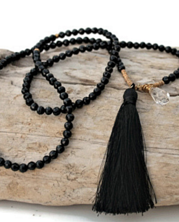 Long black beaded tassel necklace on wood