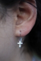 silver cross earring on ear