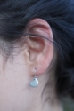 small silver heart earrings on ear