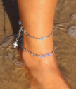two layered anklets on foot in sand and water