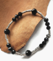 silver and black gemstone bracelet on wood