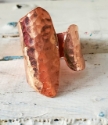 Wide hammered copper wrap ring on white distressed wood