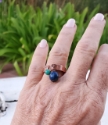 Wearing an artisan copper cuff ring with blue gemstone on white distressed background