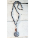 Long  Blue-gray pearl necklace with a silver French coin on white wood