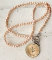 Peach pearl necklace with Gold German coin on white wood