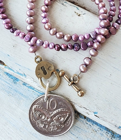 Silver New Zealand purple pearl coin necklace on white distressed wood