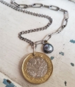 Mixed metal coin and chain necklace on white wood