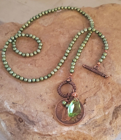 Green pearl, crystal old Irish coin necklace on rock
