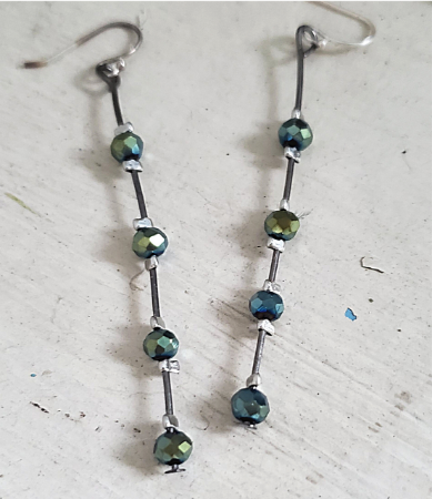 tiny dark green crystal stick earrings on white wood