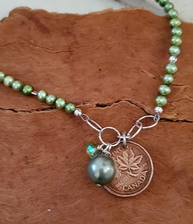 Canadian coin green pearl necklace on wood