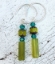 green gemstone stick earrings on white distressed wood