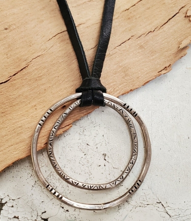 Patterned Silver circles black leather necklace on wood