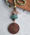 close up old vintage coin design on green pearl necklace on wood