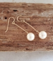 White pearl gold stick earrings on wood