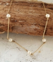 Soft white pearl gold stick necklace on wood