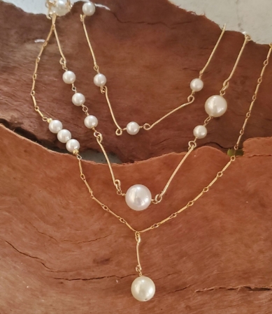 three pearl necklaces layered on wood