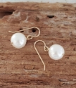 single white pearl gold wire earrings on wood