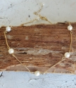 white pearl gold bar necklace draped over wood
