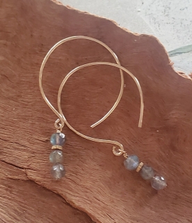 Gray gemstone gold hoop earrings on wood