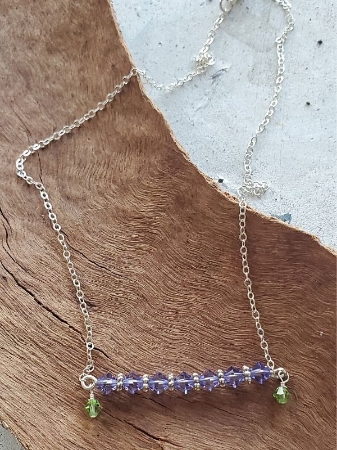 Purple and green Swarovski crystal bar necklace on wood