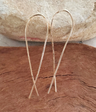 gold arc earrings on rock