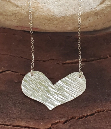 silver heart necklace on wood