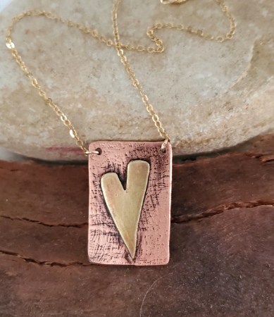 brass and copper heart gold chain necklace on wood