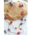 Long purple, pink, yellow-orange pom pom necklace on rock
