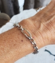 silver oval shape center rolo chain bracelet on arm