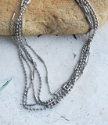Slinky silver mixed chain layered necklace on rock