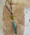 green & teal gemstone corded stick necklace on rock