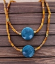 two golden brown, blue round agate gemstone necklaces on wood