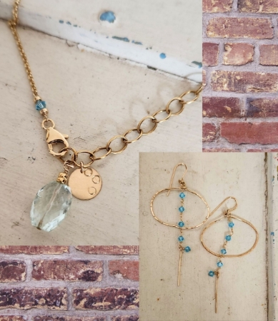 gold chain light blue gemstone necklace & hoop crystal chain earrings on brick background