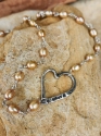 Unique handcrafted silver heart pearl necklace on rocks