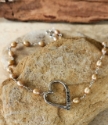 handcrafted silver open heart pearl necklace on rock wood
