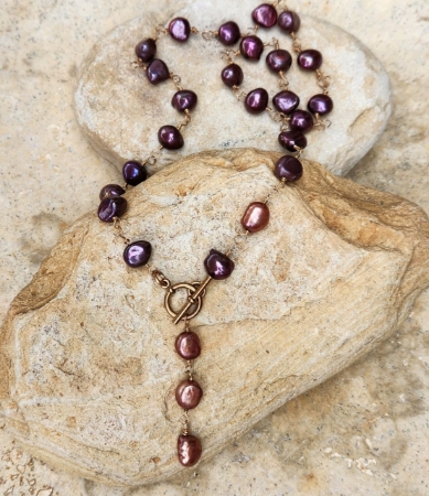 Artisan wire wrapped purple pearl toggle necklace on rocks full view