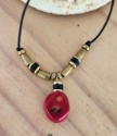Black cord, red coral, brass necklace on wood
