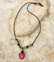 red sponge coral brass black bead necklace on rock full view