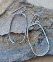 long silver elliptical hoop earrings on stones