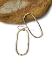 long hammered gold elliptical earrings on a rock