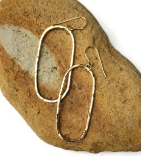 handcrafted, hammered-long-gold-elliptical earrings on rock
