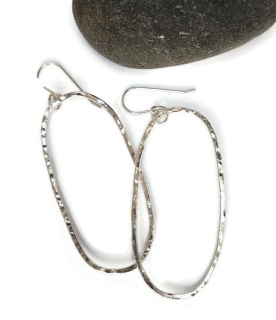 silver hammered elliptical earrings against black rock