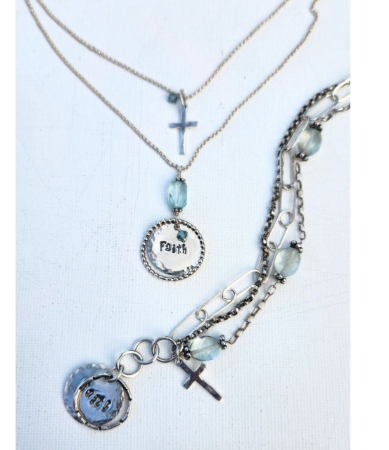 silver chain faith necklace and multi chain bracelet on pale blue background