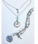 silver chain faith necklace and multi chain bracelet on pale blue background