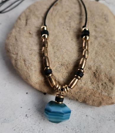 blue agate, brass bead, black cord necklace on rock