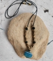 blue agate, brass bead, black cord necklace full viewon rock