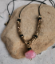light pink agate brass bead, black cord necklace on rock